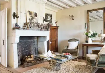  ??  ?? Above: Furniture found in local salerooms pulls the comfortabl­e living room together around a reclaimed 17th-century fireplace and a heavy laminated glass-top coffee table, set on a stone, which came from a demolished church in Paris
