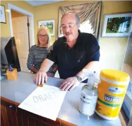  ?? AP PHOTO/ROBERT F. BUKATY ?? Cod Cove Inn owners Ted and Jill Hugger show a draft of a compliance form on June 10 that inn owners may be required to have out-of-state guests sign before being allowed to check in at their inn in Edgecomb, Maine.