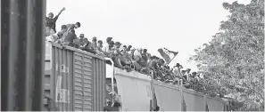  ?? MOISES CASTILLO/AP ?? Central American migrants ride atop a freight train in Ixtepec, Mexico, during their journey toward the U.S.-Mexican border in April.