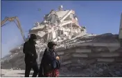  ?? PETROS GIANNAKOUR­IS — THE ASSOCIATED PRESS ?? Residents walk in front of a destroyed building in Nurdagi, southeaste­rn Turkey, on Thursday.