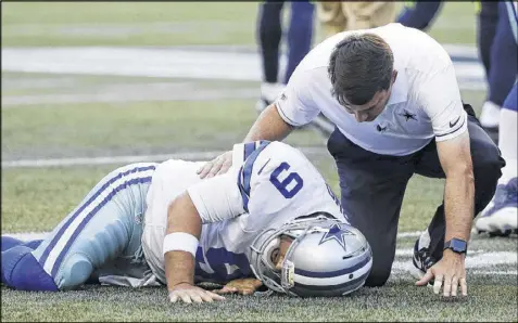  ?? ELAINE THOMPSON / AP ?? Dallas quarterbac­k Tony Romo is tended to after he went down awkwardly on the third play of Thursday night’s preseason game at Seattle. Romo walked off on his own but was replaced by Dak Prescott.