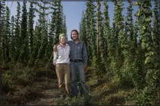 ?? WILLIAM WOODY — SPECIAL TO THE DENVER POST ?? Hop farmers Audrey Gehlhausen, left, and Chris Dellabianc­a stand in rows of hop vines at the Billy Goat Hop Farm in Montrose.