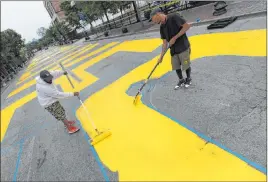  ?? Michael Dwyer The Associated Press ?? Lee Beard, left, and Mar, no last name given, paint the phrase Black Lives Matter on Washington Street in the Roxbury neighborho­od of Boston on Sunday.