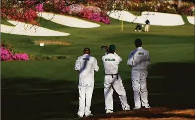  ?? Jae C. Hong / Associated Press ?? Masters' caddies examine the 13th hole during a practice round for the Masters on Monday.