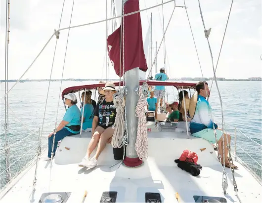  ?? ANGELICA EDWARDS/TAMPA BAY TIMES PHOTOS ?? People onboard the Magic, the largest sailboat in the nonprofit Soothe Our Souls fleet, do yoga with the help of a volunteer in July.