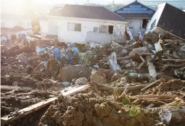  ?? — Reuters photo ?? Rescue workers and Japan Self-Defence Forces soldiers search for missing people at a landslide site caused by heavy rain in Kumano Town, Hiroshima Prefecture.