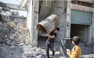  ?? PICTURE: REUTERS ?? SCAVENGING: A man carries an oil drum as people collect steel from a destroyed building in Mosul, yesterday.