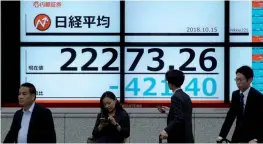  ??  ?? Pedestrian­s stand in front of an electronic indicator showing share prices of the Tokyo Stock Exchange in Tokyo yesterday. The benchmark Nikkei index dropped more than 1.8%.