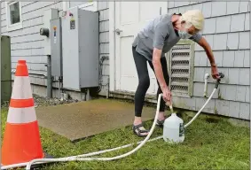  ?? DANA JENSEN/THE DAY ?? Sheila Wertheimer of Old Lyme fills gallon jugs with water her family will use for their toilets from a garden hose Friday that was available for people to use at the respite center at the Lymes’ Senior Center in Old Lyme. Wertheimer’s daughter Rachel was around the corner of the building charging their electronic devices at the charging station. Bottled water was not available.