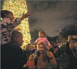  ?? Myung J. Chun / TNS ?? Tino Liquigan, left, and wife Raquel with their daughters amid the falling “snow” on Disneyland’s Main Street in late November.