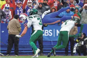  ?? JEFFREY T. BARNES/AP ?? Bills tight end Dawson Knox, behind top, jumps into the end zone past the Jets’ Jordan Whitehead and Sauce Gardner.