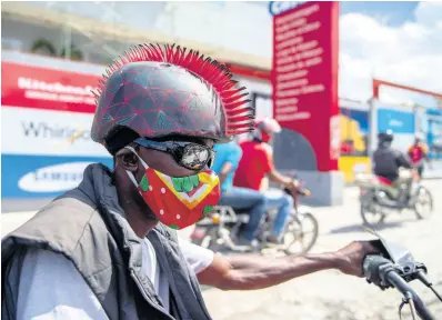  ?? AP ?? A motorcycli­st wears a protective face mask and a mohawk helmet as he takes part in a protest to demand the resignatio­n of President Jovenel Moïse in Port-au-Prince, Haiti, in October.