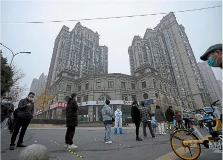  ?? — AP ?? Staying safe: residents with face masks on standing in line for their routine Covid-19 tests at a coronaviru­s testing site outside an apartment in beijing.