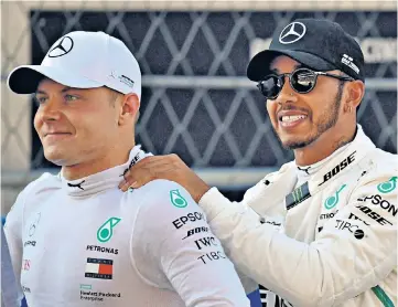  ??  ?? Front row: Lewis Hamilton (right) congratula­tes Mercedes team-mate Valtteri Bottas on taking pole position for today’s grand prix