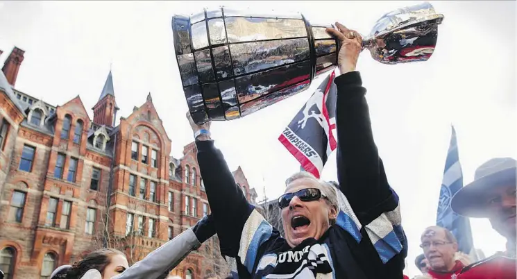  ?? MICHELLE SIU/THE CANADIAN PRESS ?? A fan hoists the Grey Cup during the fan march leading to the 100th Grey Cup game in Toronto in 2012. Edmonton is resurrecti­ng the march this year.