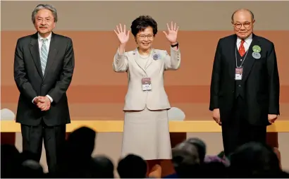  ?? Reuters ?? Carrie Lam waves after she won the election for Hong Kong’s next Chief Executive as other candidates John Tsang (left) and Woo Kwokhing stand next to her in Hong Kong. —