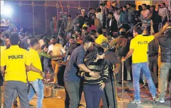  ??  ?? AFP A man helps a woman as police personnel manage the crowd during New Year celebratio­ns in Bengaluru on January 1.