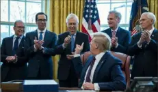  ?? Evan Vucci/Associated Press ?? President Donald Trump hands a pen to Senate Majority Leader Mitch McConnell, R-Ky., on Friday after signing the coronaviru­s stimulus relief package in the Oval Office at the White House. From left are White House chief economic adviser Larry Kudlow, Treasury Secretary Steven Mnuchin, Mr. McConnell, Mr. Trump, House Minority Leader Kevin McCarthy, R-Calif., and Vice President Mike Pence.