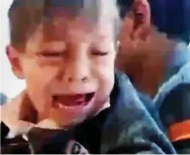  ??  ?? Traumatise­d: The little boy cries as he is pulled from the collapsed school yesterday