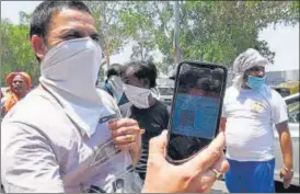  ??  ?? A liquor shop volunteer checks the e-coupon of a customer as per Delhi government guidelines before he queues up at a liquor shop in New Delhi on Saturday. MOHD ZAKIR/HT PHOTO