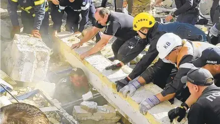  ?? NATIONAL POLICE OF UKRAINE VIA AP ?? Emergency responders and police officers work to save an injured officer from under the rubble following a Russian attack in Kryvyi Rih, Ukraine, on Friday. The attack killed one police officer and injured 73 other people, including nine officers.