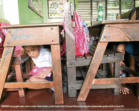  ?? JUNJIE MENDOZA/CEBU DAILY NEWS ?? GRADE one pupils take cover under their desks at the Cebu City Central School during the nationwide quake drill on June 22.