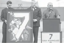  ?? Rick Yeatts / Getty Images ?? Ivan Rodriguez, right, basks in the moment of having his No. 7 jersey retired by the Rangers on Saturday. It marked the third jersey retirement for the Rangers.