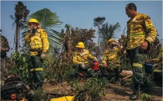  ?? FILE PHOTOS BY VICTOR MORIYAMA/THE NEW YORK TIMES ?? Agents of the Brazilian Institute of the Environmen­t rest during an effort to extinguish a blaze set to clear land near Rio Pardo, in Brazil’s Rondônia state. After fending off criticism on rainforest destructio­n, President Jair Bolsonaro caved to pressure and took steps to curb deforestat­ion and forest fires.