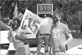  ?? JOHN RAOUX/AP PHOTO ?? Cristian Cardona, right, an employee at a McDonald’s, attends a rally for a $15 an hour minimum wage last week in Orlando, Fla.