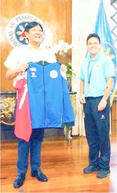  ?? PHOTOGRAPH COURTESY OF PBBM ?? TANHAI Annis (right) of the national women’s football team gives President Ferdinand Marcos Jr. their official jacket and jersey during their courtesy call at Malacañang late Wednesday.