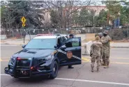  ?? EDDIE MOORE/JOURNAL ?? New Mexico State Police and National Guard troops talk outside the state Capitol in Santa Fe on Monday. Security fencing has been installed, and some roads in the area have been closed to traffic amid reports of possible riots and civil unrest.