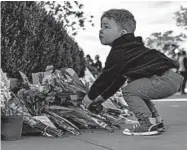  ?? SAMUEL CORUM/GETTY ?? A young boy places flowers Saturday at a makeshift memorial for Supreme Court Jutsice Ruth Bader Ginsburg.