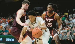  ?? MARTA LAVANDIER/AP ?? Miami guard Nijel Pack dribbles the ball between Virginia Tech guard Hunter Cattoor, left, and forward Justyn Mutts during Tuesday night’s game in Coral Gables, Florida.