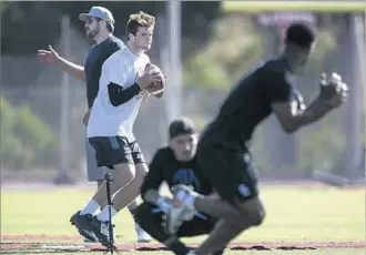  ??  ?? DARNOLD WORKS OUT with private quarterbac­ks coach Jordan Palmer, left, at San Clemente High, where Darnold began as a receiver and linebacker before taking over as a sophomore.