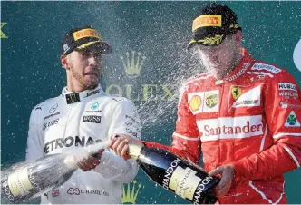  ?? —AFP ?? MELBOURNE: This file photo taken on March 26, 2017 shows Ferrari’s German driver Sebastian Vettel (R) spraying champagne with runner-up Mercedes’ British driver Lewis Hamilton (L) on the podium at the end of the Australian Grand Prix in Melbourne....