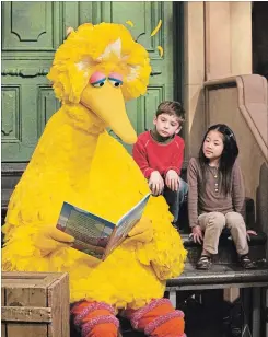  ?? MARK LENNIHAN THE ASSOCIATED PRESS ?? Big Bird reads to Connor Scott and Tiffany Jiao during a taping of “Sesame Street.” Early on, Spinney decided to play the eight-foot-two character as a child.