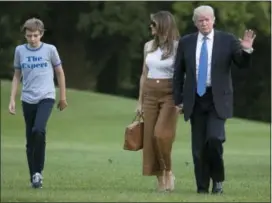  ??  ?? President Donald Trump waves as he walks with first lady Melania Trump and their son, Barron, from Marine One across the South Lawn to the White House Sunday.