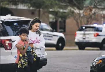  ?? Billy Schuerman Virginian-Pilot ?? JOSELIN GLOVER holds her 9-year-old son, Carlos, as they leave Richneck Elementary School in Newport News, Va., on Friday after a student shot a teacher. The police chief said the shooting was not accidental.