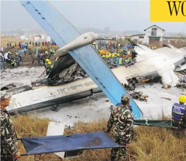  ?? NIRANJAN SHRESHTA/THE CANADIAN PRESS/THE ASSOCIATED PRESS ?? Rescuers carry stretchers near the ruins of a passenger plane from Bangladesh that crashed at the airport in Kathmandu, Nepal, on Monday. The plane, a Bombardier Dash 8 turboprop, was carrying 71 people at the time.