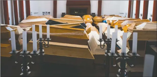  ?? (AP/Markus Schreiber) ?? Coffins containing deceased people wait in the worship room of the crematoriu­m in Meissen, Germany, before cremation. For those who died with the coronaviru­s, the coffins are marked with the word “covid” as a warning.
