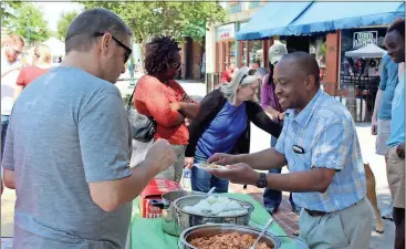  ??  ?? ABOVE: Michael Nyamuranga (right) prepares a plate of traditiona­l Zimbabwean cuisine for Joe Young.
LEFT: Taeleigh Jenkins tries her hand at playing the Rome Knitterati piano.
BELOW: Javier Roman (left) and Katelyn Roman use their hands to smooth out...