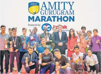  ?? PHOTOS; HTCS ?? Divya Chauhan and Dr Aseem Chauhan with the winners of the Amity Gururgram Marathon held at Leisure Valley Park, Gurgaon