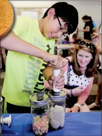  ?? NWA Media/BEN GOFF ?? Tisha Berger looks on as her son Caden, 10, of Bentonvill­e uses Mason jars at the Bentonvill­e Public Library in an experiment during a preview of the new Amazeum children’s museum under constructi­on.