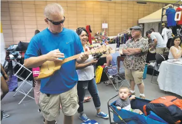  ??  ?? Theia Mendez, 2, (left) and Leela Rush, 3, dance during the Aloha Poly Fest as Barbara Tober performs. Douglas Bias tries a Tahitian ukulele as Jonah Avalos, 1, watches with mom Sheree at the festival.