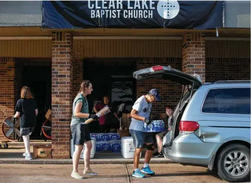  ?? Photos by Godofredo A. Vásquez / Staff photograph­er ?? Clear Lake Baptist Church volunteer Yam Hendra, center, loads bottled water into a van in line at the church’s pandemic-born food pantry.