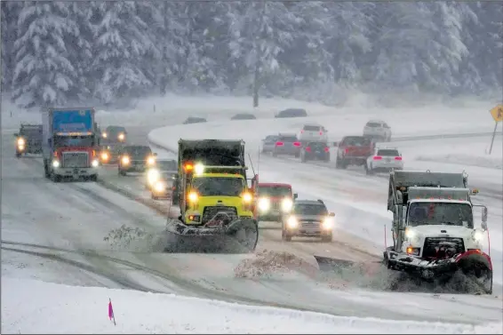  ?? (AP/Ted S. Warren) ?? Washington Department of Transporta­tion snowplows work Thursday on a stretch of eastbound Interstate 90 as snow falls near Snoqualmie Pass in Washington state.