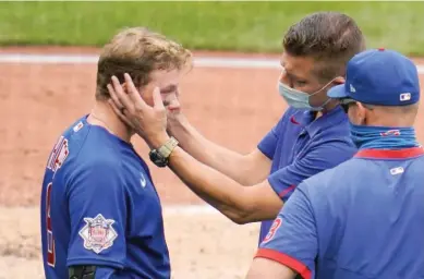  ?? AP ?? The Cubs’ Ian Happ is examined by trainer PJ Mainville after fouling a ball off his face in the fourth inning Thursday.