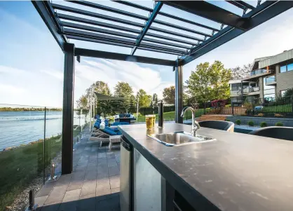  ??  ?? Sous la pergola en aluminium à lamelles rétractabl­es, une cuisine extérieure munie d'un gril intégré à même le comptoir en béton poli permettra de profiter aussi bien d'un bon repas que d'une vue exceptionn­elle, beau temps, mauvais temps.