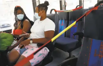  ?? Scott Strazzante / The Chronicle ?? Kayla Fleming (left) and a friend ride a Golden Gate Transit bus with seating set up for social distancing, part of the safety measures Bay Area transporta­tion agencies are implementi­ng.