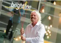  ?? LYNNE SLADKY/AP ?? Richard Branson of Virgin Group prepares to unfurl a banner during a naming ceremony for the Brightline train station in Miami in 2019. A British judge ruled in favor of Virgin group on Thursday in its lawsuit against the U.S. train company.